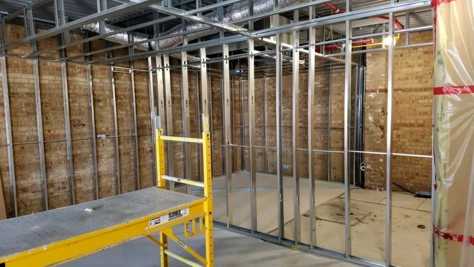 Steel stud partition walls framed inside an unfinished commercial interior, with overhead ceiling framing and ductwork